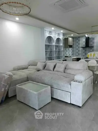 Luxurious modern living room with plush gray sectional sofa and elegant open kitchen layout.