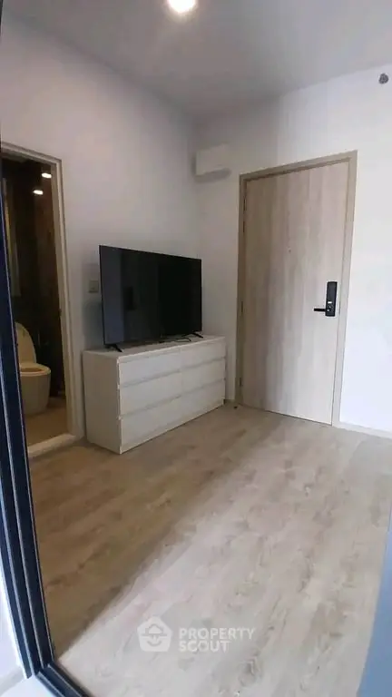 Modern apartment interior with sleek wooden flooring and a stylish TV setup, perfect for urban living.