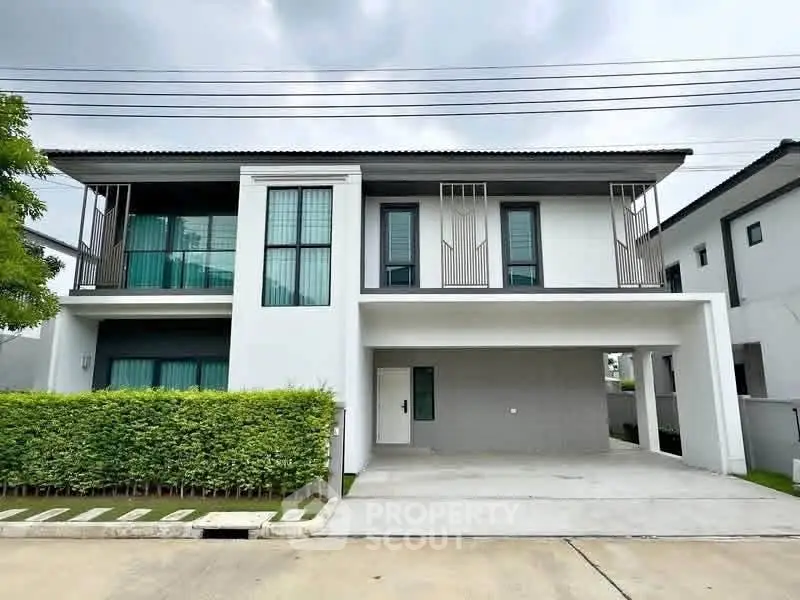 Modern two-story house with sleek design and spacious driveway in a suburban neighborhood.