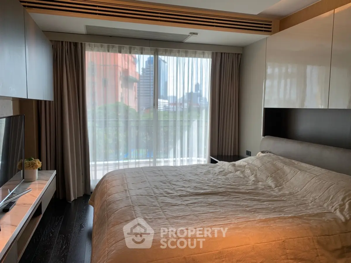 Modern bedroom with large window and city view, featuring sleek furniture and cozy bedding.