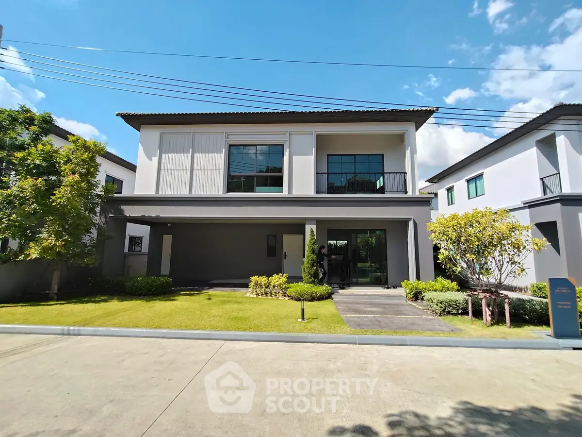 Modern two-story house with manicured lawn and large windows in a suburban neighborhood.