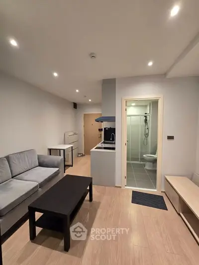 Modern open-plan living room with cozy seating and sleek kitchen area, perfect for urban living.