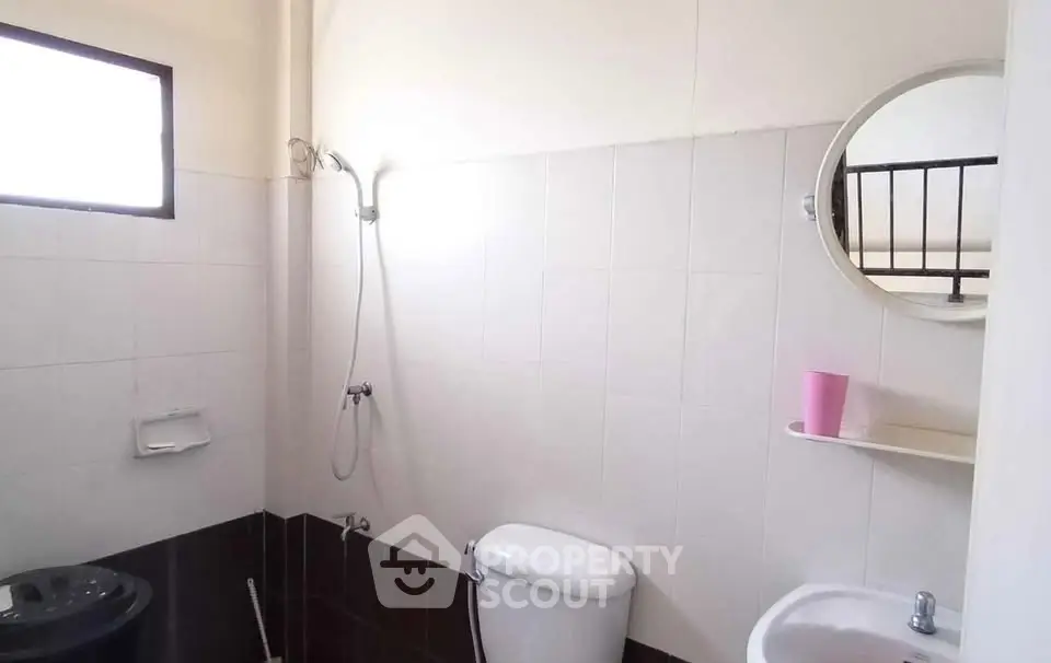 Compact bathroom with shower, toilet, and sink in a minimalist design.