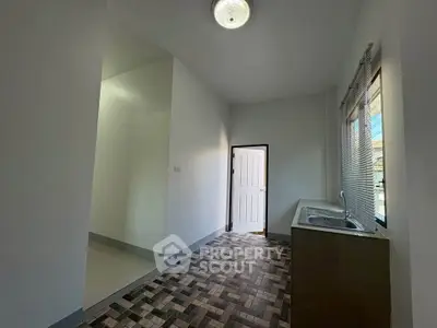 Spacious kitchen with modern sink and large window, featuring stylish tiled flooring.