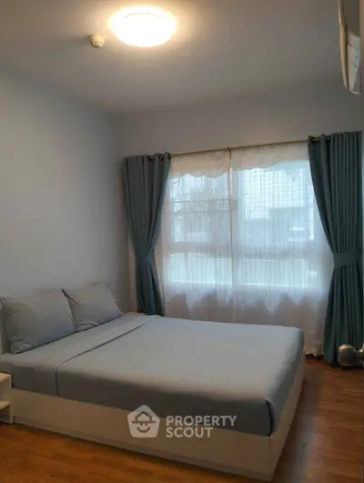 Cozy bedroom with soft lighting and large window, perfect for relaxation.