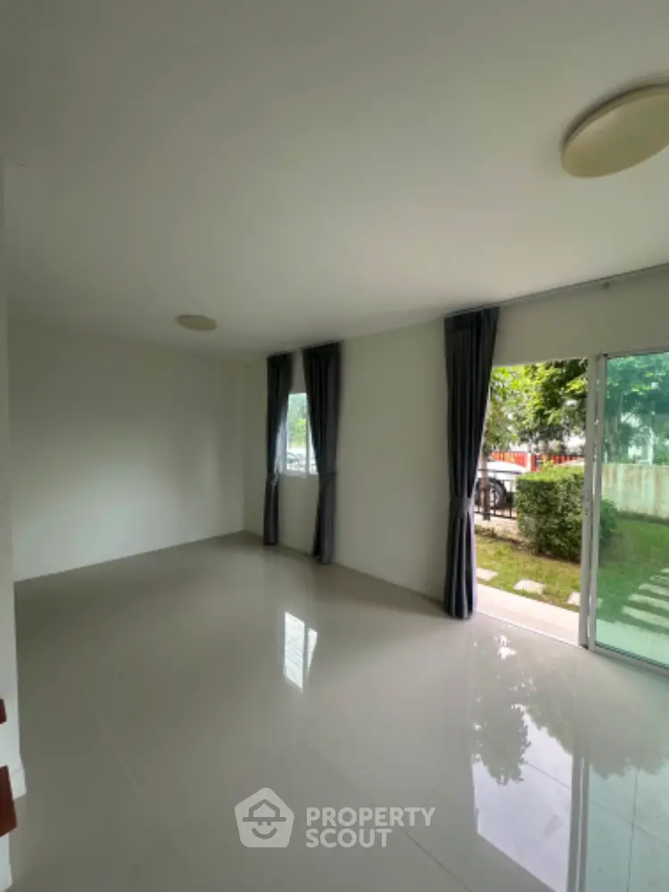 Spacious empty room with large windows and garden view, perfect for customization.