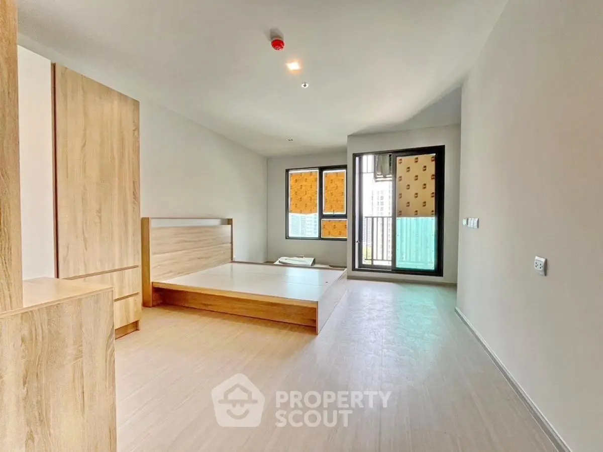 Spacious modern bedroom with wooden flooring and large windows in a minimalist design.