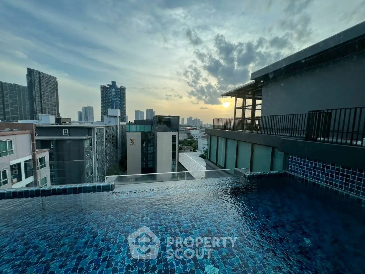 Stunning rooftop pool with panoramic city skyline view at sunset.