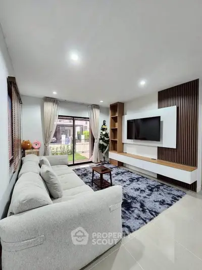 Spacious modern living room with large sofa and wall-mounted TV, perfect for relaxation.