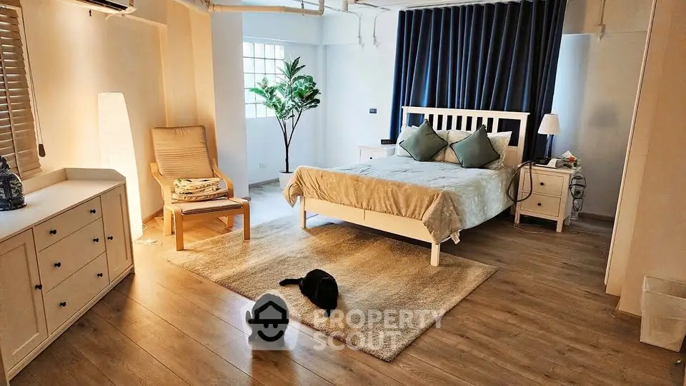 Spacious bedroom with modern decor and cozy ambiance, featuring wooden flooring and stylish furniture.