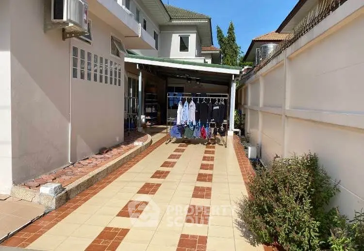 Spacious driveway with tiled pathway and laundry area in suburban home