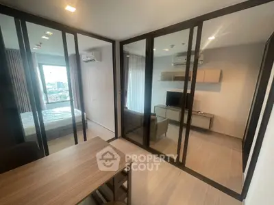 Modern apartment interior with glass partitions and city view, featuring a cozy living area and bedroom.