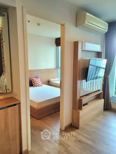 Modern apartment interior with cozy bedroom and stylish living area featuring a mounted TV and air conditioning.