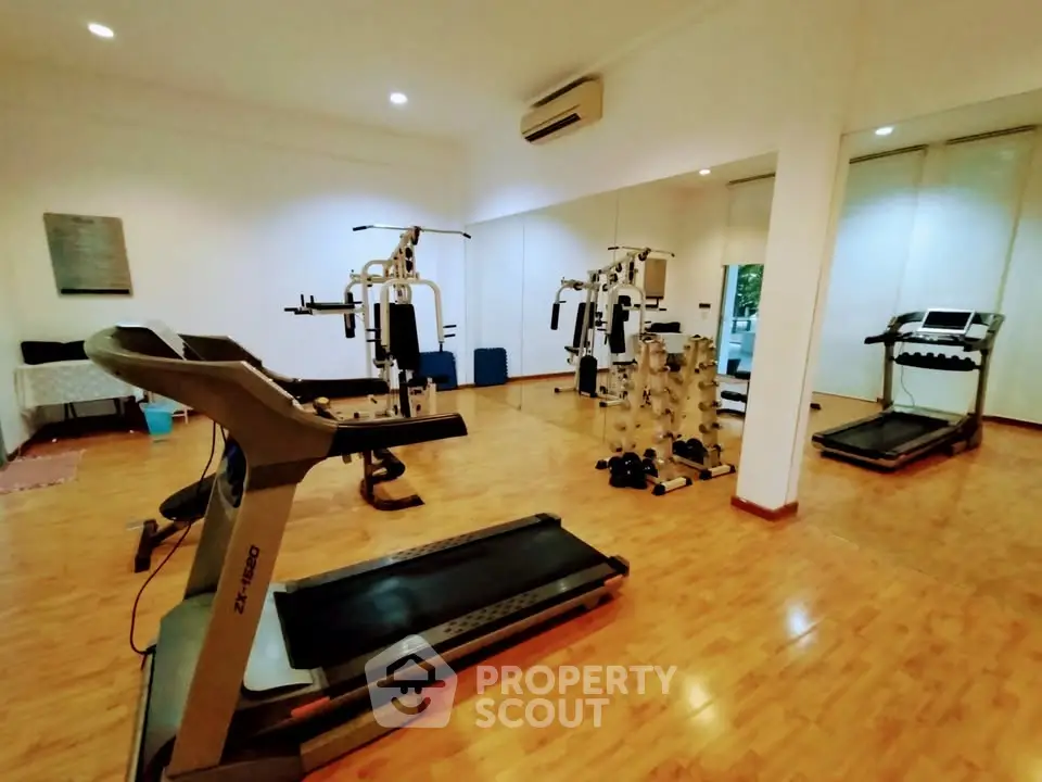 Spacious home gym with modern equipment and wooden flooring