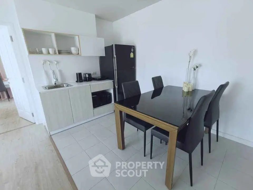 Modern kitchen with sleek dining area and black appliances in a stylish apartment.