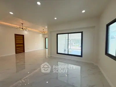 Spacious modern living room with large windows and elegant lighting fixtures.