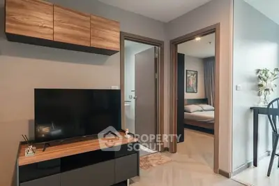 Modern apartment interior with TV and bedroom view, stylish wooden furniture, cozy ambiance.