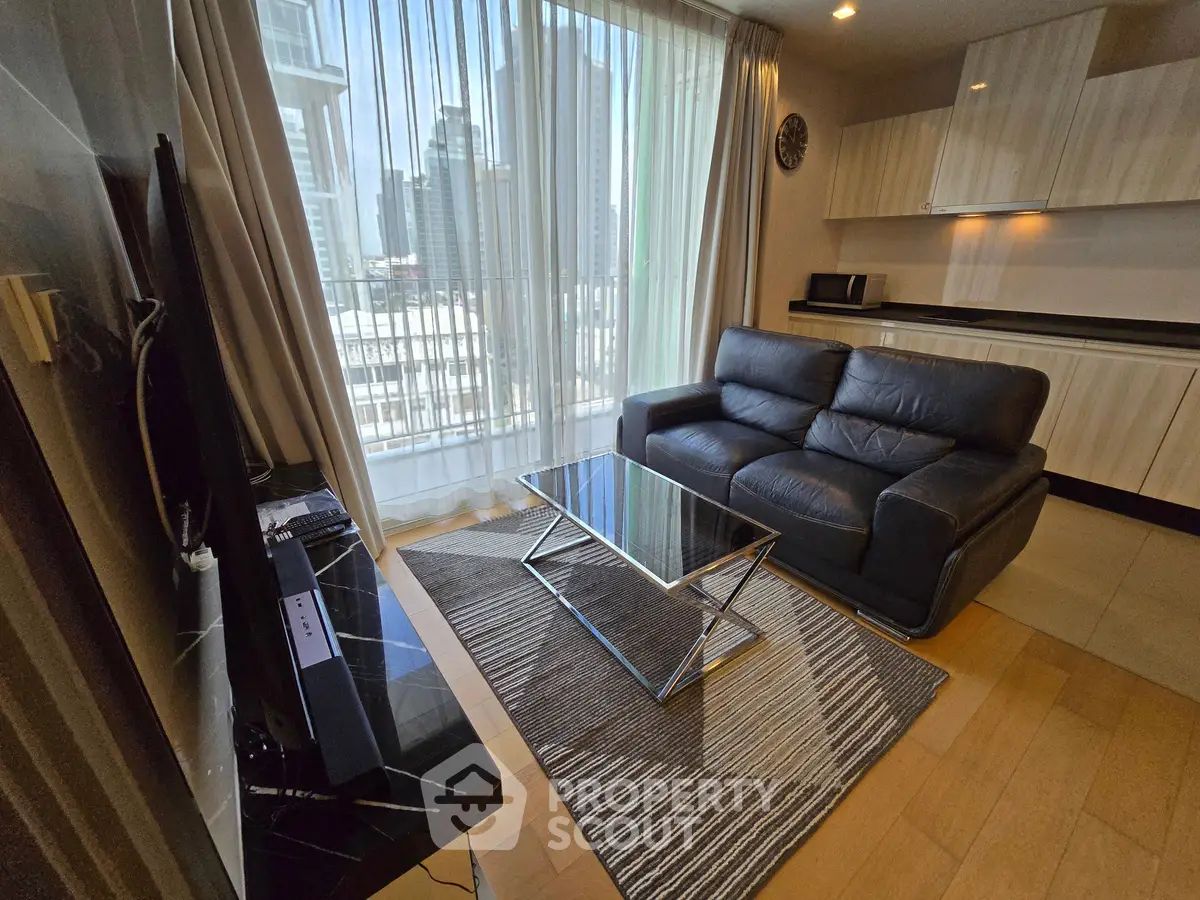 Modern living room with sleek furniture and city view, featuring a leather sofa and glass coffee table.