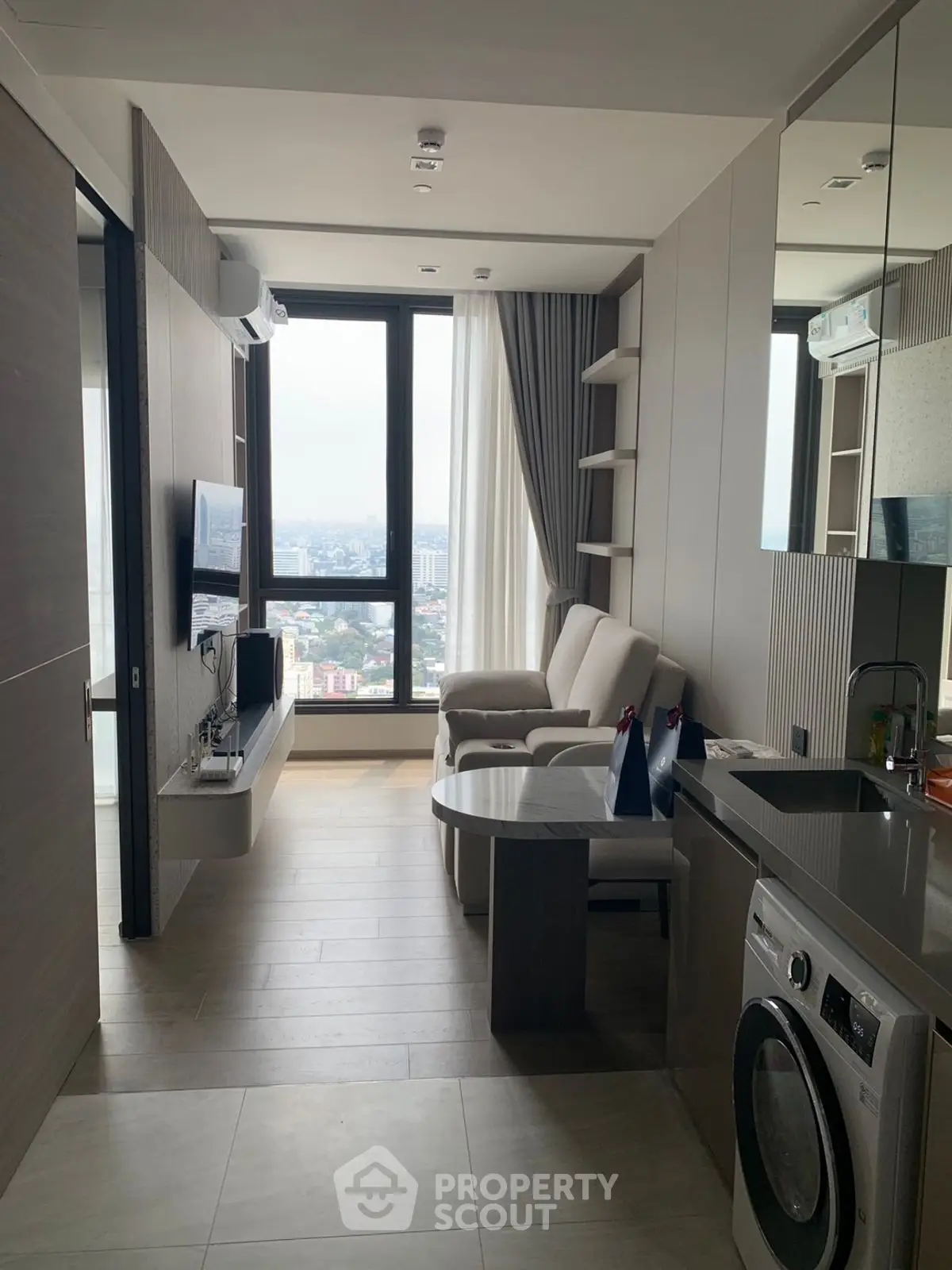 Modern living room with city view, sleek furniture, and in-unit washer