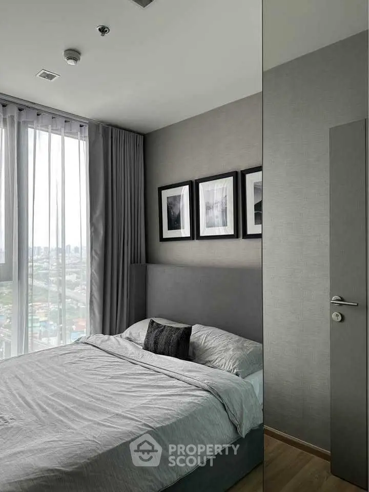 Modern bedroom with large window and stylish decor in high-rise apartment.