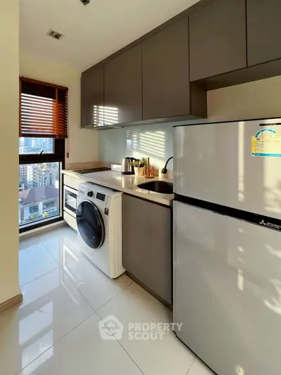 Modern kitchen with sleek appliances and city view, featuring washing machine and fridge.