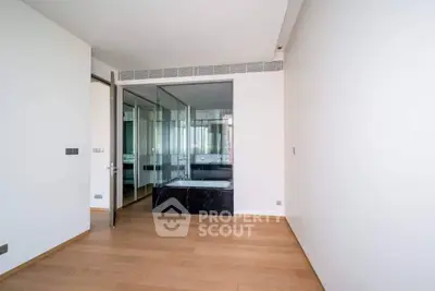Spacious modern room with wooden flooring and glass partition, ideal for versatile use.