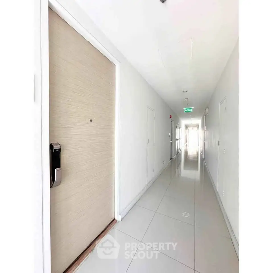 Bright and modern apartment corridor with sleek tile flooring and secure entry door.