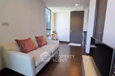 Modern living room with cozy sofa and flat-screen TV, featuring elegant wooden flooring and natural light.