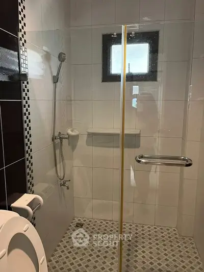Modern bathroom with glass shower enclosure and tiled walls.