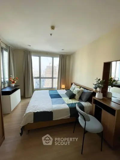 Spacious bedroom with city view, modern decor, and natural light in a high-rise apartment.