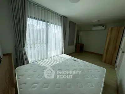 Spacious bedroom with large window and modern furnishings, perfect for comfortable living.