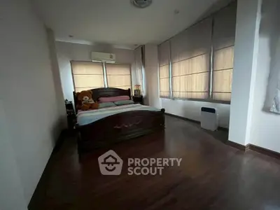 Spacious bedroom with wooden flooring and large windows for natural light.