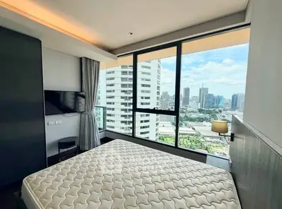 Modern bedroom with city view in high-rise apartment, featuring large windows and sleek design.