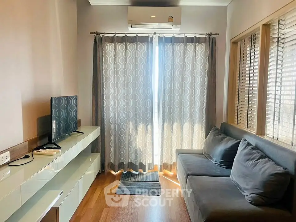 Cozy living room with modern decor, large window, and comfortable seating in a stylish apartment.