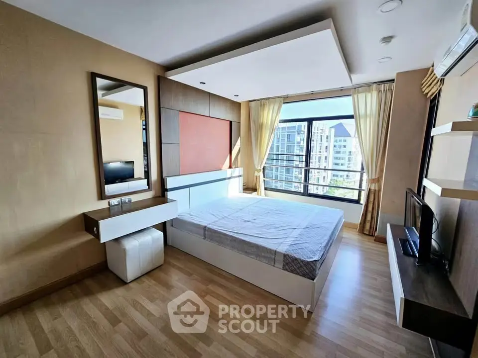 Spacious bedroom with modern decor and large window offering city views