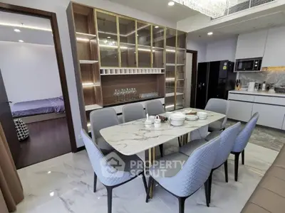 Luxurious dining area with marble table, elegant chairs, and modern kitchen in open layout apartment.