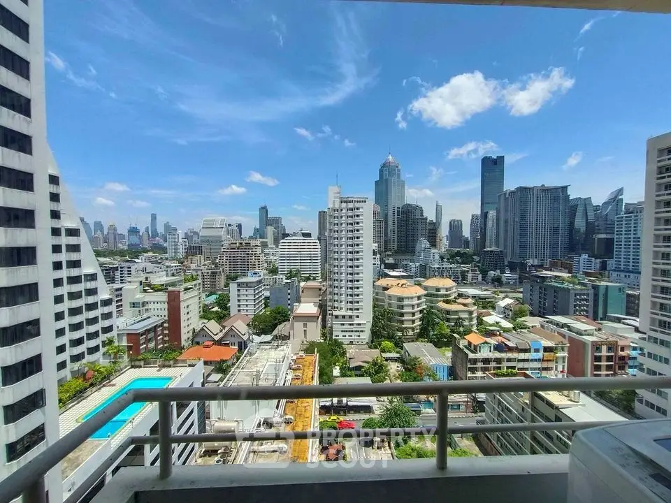 Stunning cityscape view from a high-rise balcony overlooking urban skyline and pool.