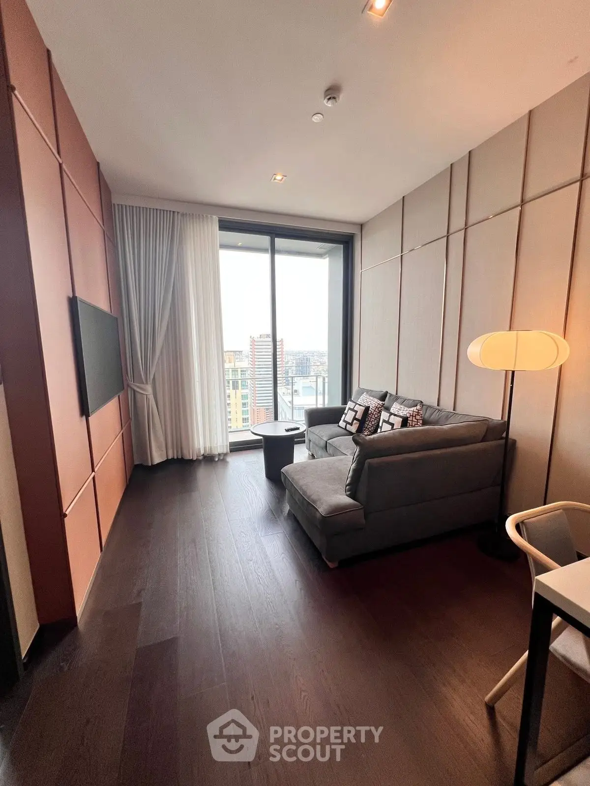 Modern living room with city view, featuring sleek furniture and floor-to-ceiling windows.