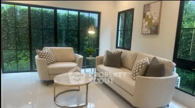 Elegant living room with modern furniture and large windows overlooking lush greenery.