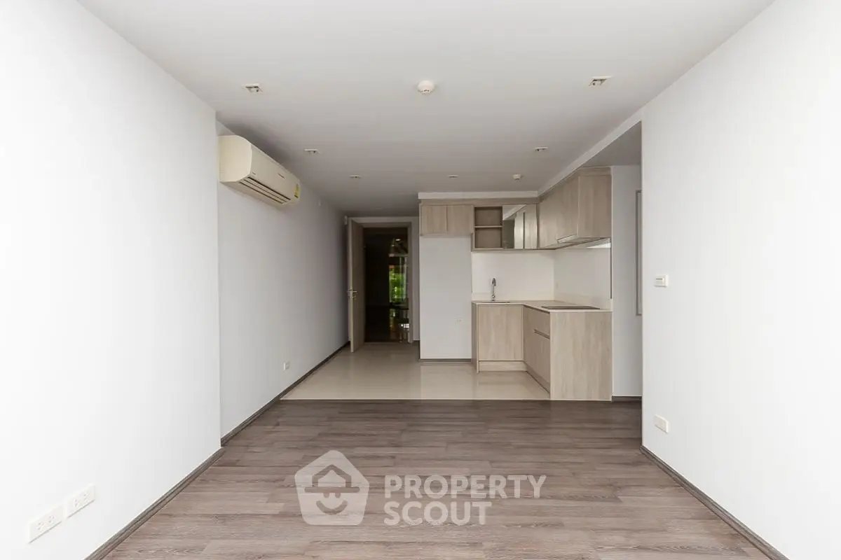 Spacious open-plan living room with modern kitchen in minimalist apartment.