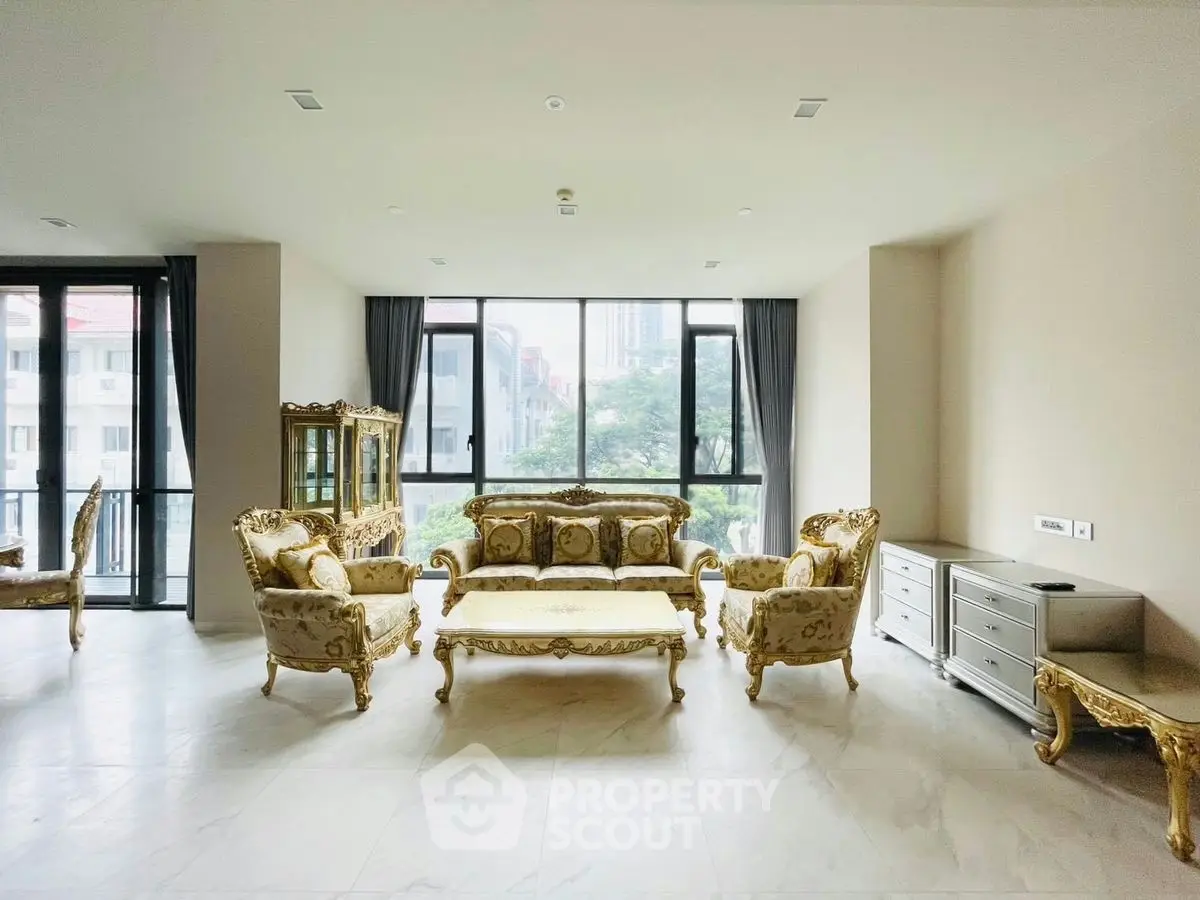 Luxurious living room with elegant gold furniture and large windows offering a serene view.