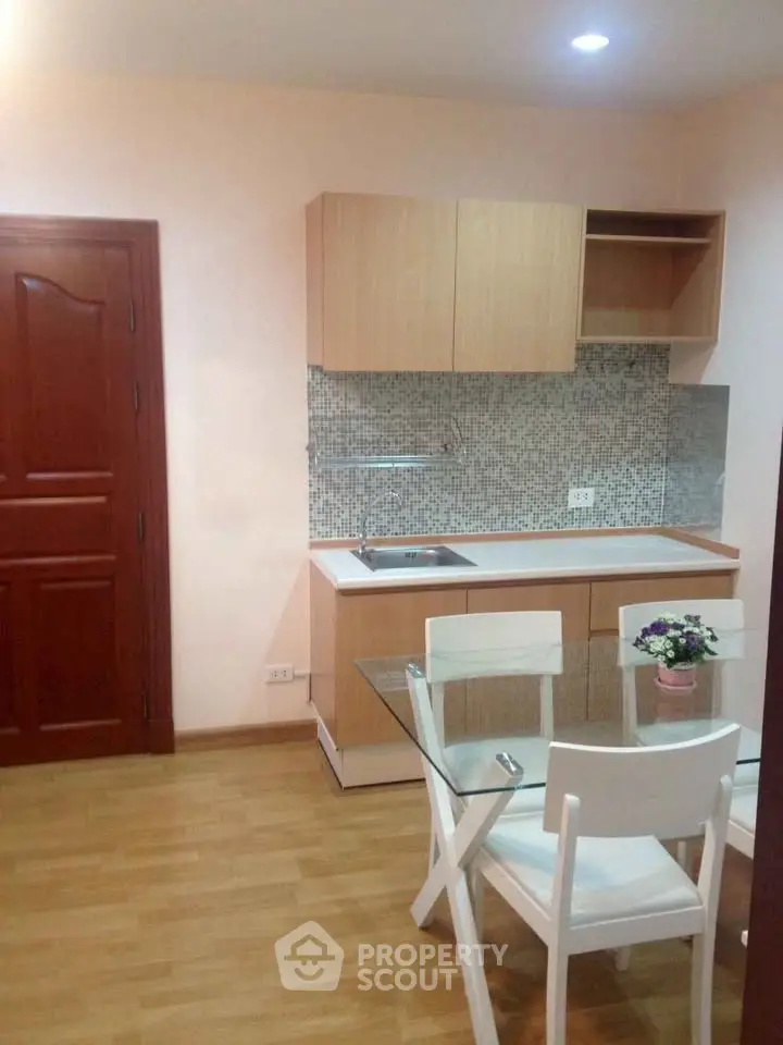 Charming kitchen with modern glass dining table and wooden cabinets in cozy apartment.