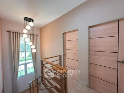 Elegant hallway with modern lighting and wooden doors, showcasing natural light through large window.