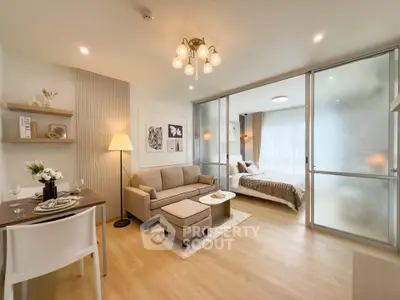 Modern open-plan living room with elegant decor and cozy bedroom separated by glass doors.