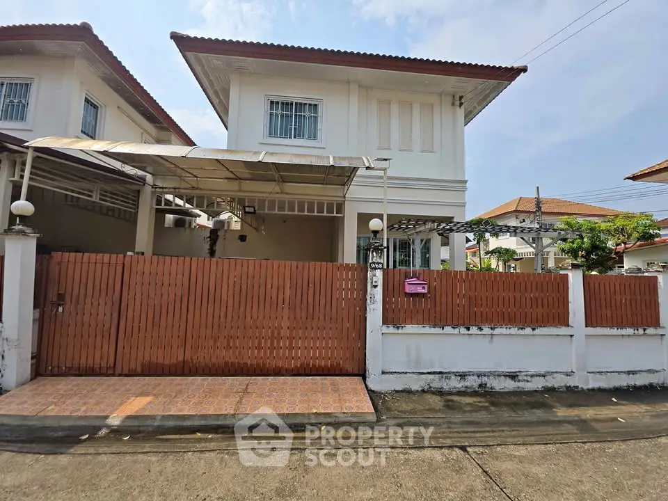 Charming two-story house with gated entrance and tiled driveway in a serene neighborhood.