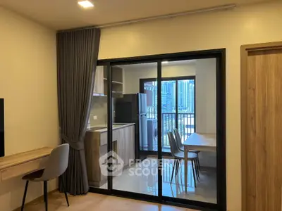 Modern apartment interior with open kitchen and dining area, featuring city view from balcony.