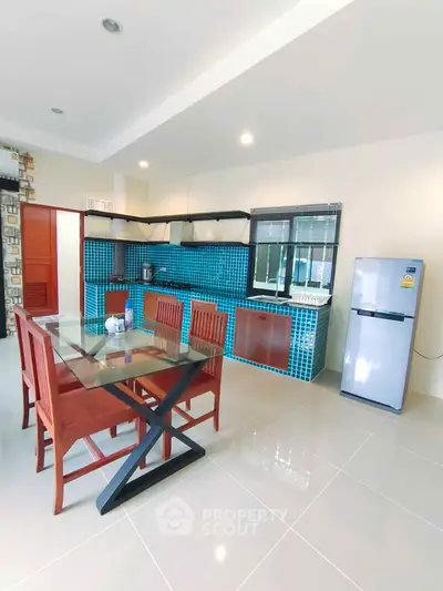 Modern kitchen with blue tile backsplash, dining table, and stainless steel fridge in open layout.