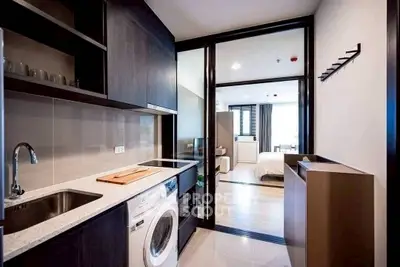 Modern apartment kitchen with washing machine and open layout to bedroom