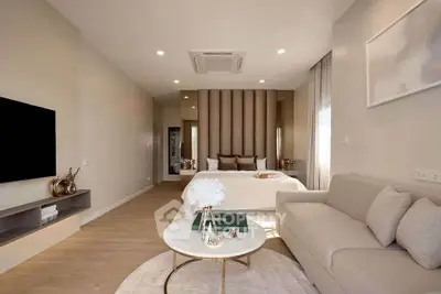 Modern open-plan living room with cozy sofa and elegant bedroom area