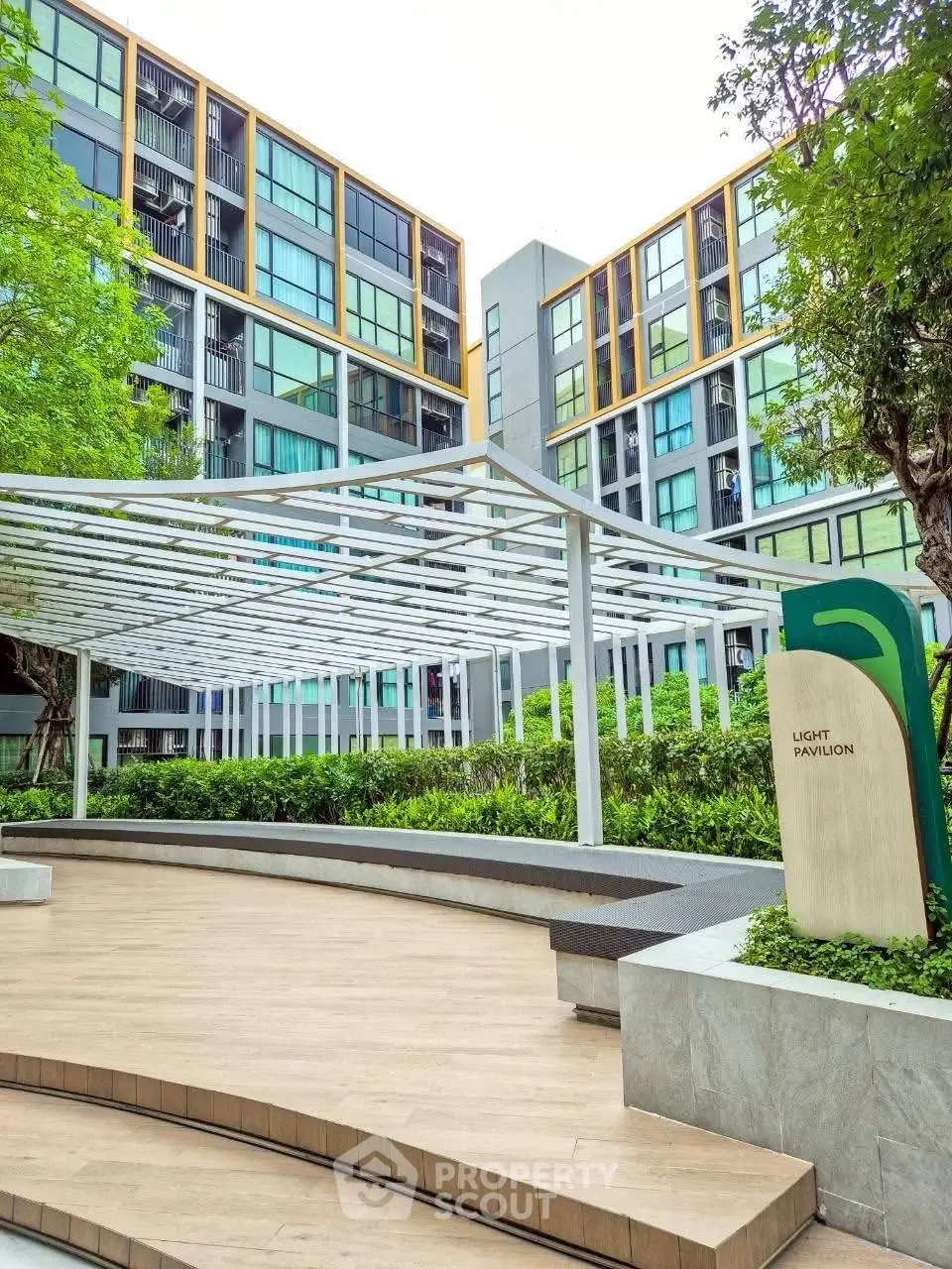 Modern apartment building with lush greenery and outdoor pavilion area.